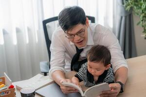 Father reading a book to his baby in a cozy office setting during the daytime photo