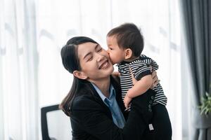 Mother sharing a joyful moment with her infant child in a modern office setting during daytime photo