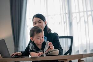 Working parent assists toddler as they explore a book in a well-lit home office setting during the afternoon photo