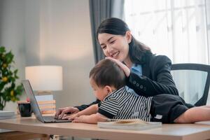 Working mother engages with toddler while focused on laptop in a bright home office setting photo