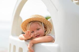 Child playing and waving from colorful playground structure at beach on sunny day photo