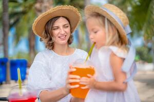 Relaxing day at the beach with mother and daughter enjoying refreshing drinks under palm trees photo