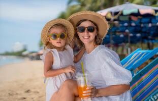 Family enjoys a sunny day at the beach under palm trees with colorful beach chairs and refreshing drinks photo