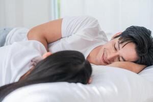 Couple sharing a joyful moment while lying together on a bed in a cozy room during the morning light photo