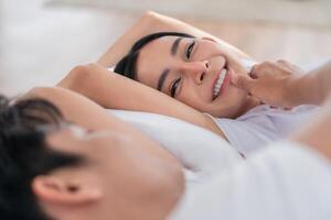 Couple enjoying a cozy moment together in a bright and airy bedroom while sharing smiles and laughter photo