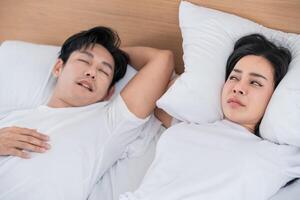 Couple sleeping in bed with contrasting expressions during morning light in a cozy bedroom setting photo