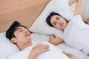 Couple in bed with one partner snoring, causing disruption at morning in a cozy bedroom setting photo