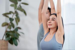 Yoga practitioners engage in a stretching routine in a bright indoor space surrounded by greenery photo