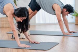 Couple practicing yoga at home during morning workout session in living room photo