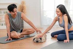 Healthy couple enjoys a relaxed yoga session at home with their playful pug dog in the morning photo