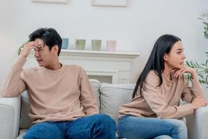 Couple sitting apart in a living room during an argument while feeling emotional and disconnected from each other photo