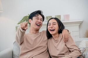 Joyful couple sharing laughter while relaxing on a cozy sofa at home during a sunny afternoon photo