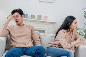 Couple sits apart in tense silence as frustration builds during a disagreement at home in the afternoon photo