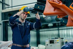 Worker adjusting a robotic arm in an industrial setting during a daytime operation photo