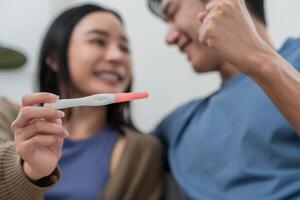Couple celebrates positive pregnancy test in cozy indoor setting with smiles and excitement photo