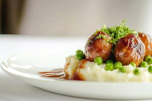 close-up of meatballs with mashed potatoes and green peas on a white plate photo with blurred background