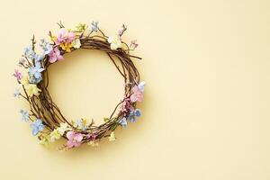 top view beautiful spring composition delicate floral wreath made of twigs and pastel flowers on a pale yellow background with copy space photo