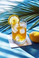 a glass of lemonade with ice and a lemon on a blue table photo
