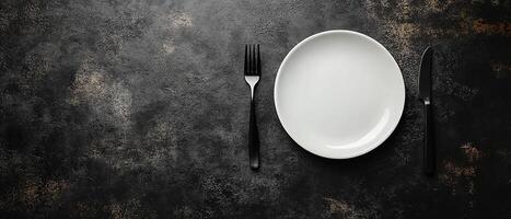 Top View of a Modern Black and White Dinner Setup Featuring a Simple Plate and Matte Black Fork and Knife with Copy Space photo