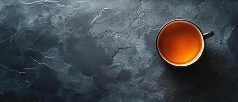 Top View of a Black Cup Filled with Hot Tea on a Dark Textured Slate Stone Background photo