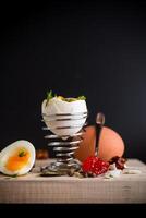 simple breakfast. red caviar in a spoon and morning boiled egg for breakfast, isolated on black background photo
