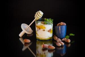 diet breakfast.homemade yogurt with kiwi, honey and nuts in a glass, isolated on black background photo