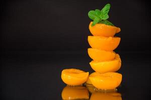 Handful of pickled peach halves on black background photo