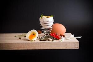 red caviar in a spoon for breakfast with a boiled egg, isolated on a black background photo