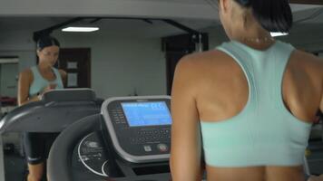 Young athletic woman is running on a treadmill at the gym. Practicing on a run machine, view from back video