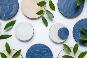 Blue and white wooden circles are arranged with green leaves, creating a stylish, contemporary design on a white background photo