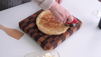 closeup woman cutting Ossetian pie with potatoes and cheese with pizza knife video