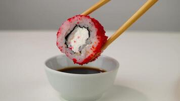 Chopsticks dip sushi roll into soy sauce, closeup of delicate culinary art video