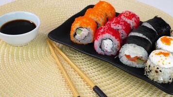 Vibrant sushi rolls with soy sauce on elegant platter and woven mat background video
