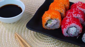 Vibrant sushi roll platter with chopsticks and soy sauce on modern table setting video