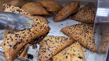 Freshly baked pastries being arranged with tongs in a bakery display case video