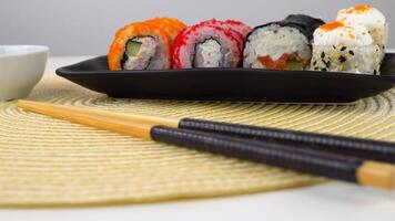 Closeup of vibrant sushi rolls on elegant table setting with chopsticks and soy sauce video
