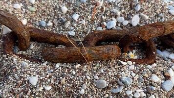 A large rusty chain on a pebble beach, washed up by a wave during a storm. High quality photos