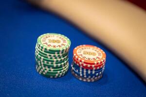 Green and red poker chips labeled Olympic Casino Poker are neatly stacked on a blue felt table. A beige surface is visible in the background. photo