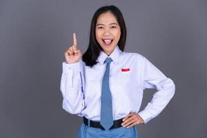 Indonesian Female High School Student in Uniform Smiling While Pointing Finger Isolated Background photo