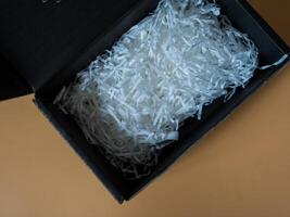 Opened cardboard box overflowing with vibrant white crinkled paper filler photo