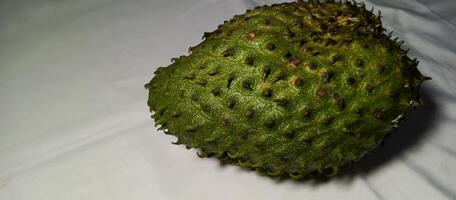 The large soursop fruit is green on a white background photo