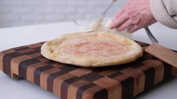 closeup woman making Ossetian pie with potatoes and cheese, adding butter video