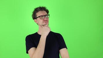 thoughtful puzzled man in who looks around touching chin and weighs pros cons of offer. isolated on green studio background, chromakey. concept - brainstorm, reasoning, analysis, fake news, good idea. video