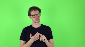 A puzzled young man bends his fingers on his hand and counts his thoughts in his mind. isolated on a green studio background, chromakey. concept - to do list, shopping, daily tasks, brainstorm video