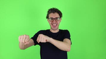 young man happy expression celebrates victory, success, dancing, actively moving his arms in front of him. isolated on green studio background, chromakey. concept - winning, rejoicing, luck, joy video