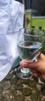 a person holding a glass of water with a white bag photo