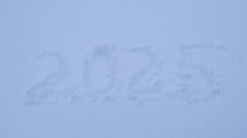 Number 2025 handwritten in snowy winter season surface. Freezing cold weather. New Year calendar date new beginning start. Snow background video