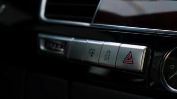Red emergency button flashing Interior of modern luxury car. Details of automatic transmission gear shift, multimedia control system, car control panel, Air Vent and dashboard inside. Prestige sport automobile. Selective focus video