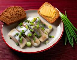 Salted herring slices with onion rings and parsley on white plate on dark grey background photo