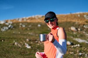 A female hiker enjoys a warm cup of tea while resting after a challenging mountain climb.A woman hiker takes a peaceful break, sipping tea and enjoying the view after a strenuous mountain climb photo